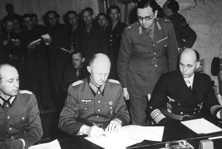 Генерал-полковник Альфред Йодль (в центре) подписывает акт о капитуляции Германии в штаб-квартире союзных войск в Реймсе, 7 мая 1945 г., 02:41 по местному времени